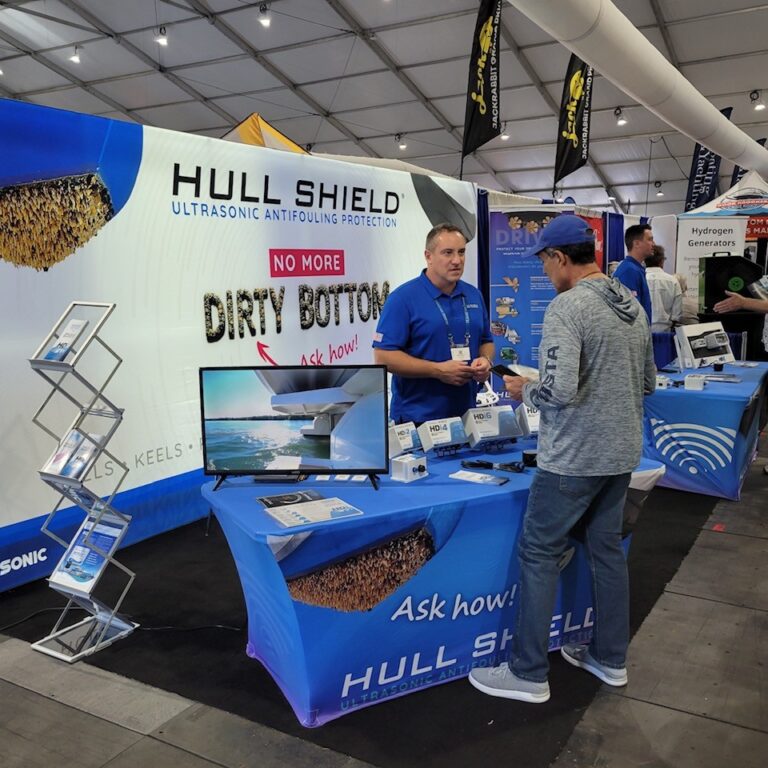 Hull Shield ultrasonic antifouling booth at a boat show, with the No More Dirty Bottom display and HDi controllers on the table